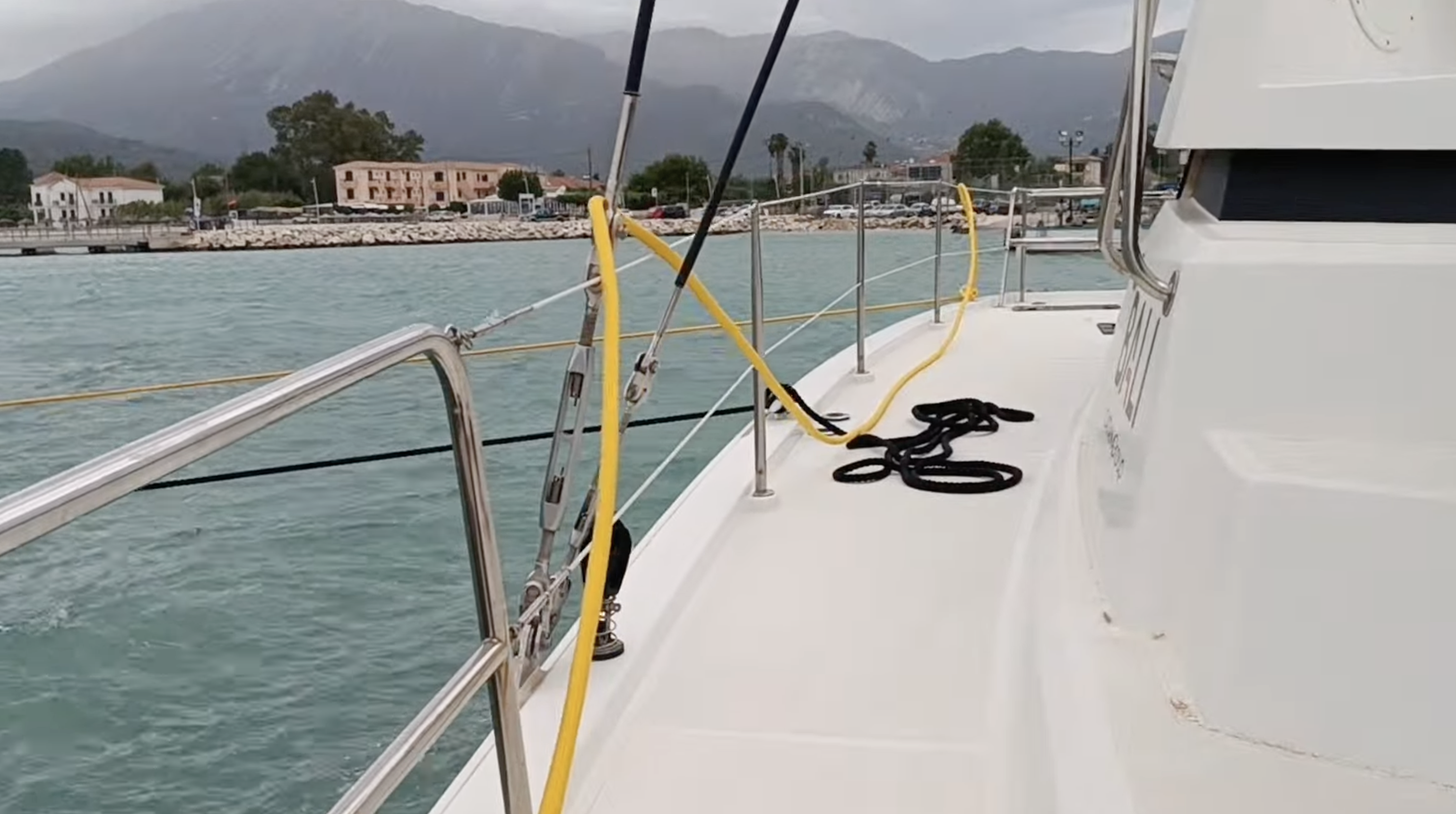 Catamaran stern-to on the Vasiliki town quay with mountains behind, overcast sky before the katabatic wind hit